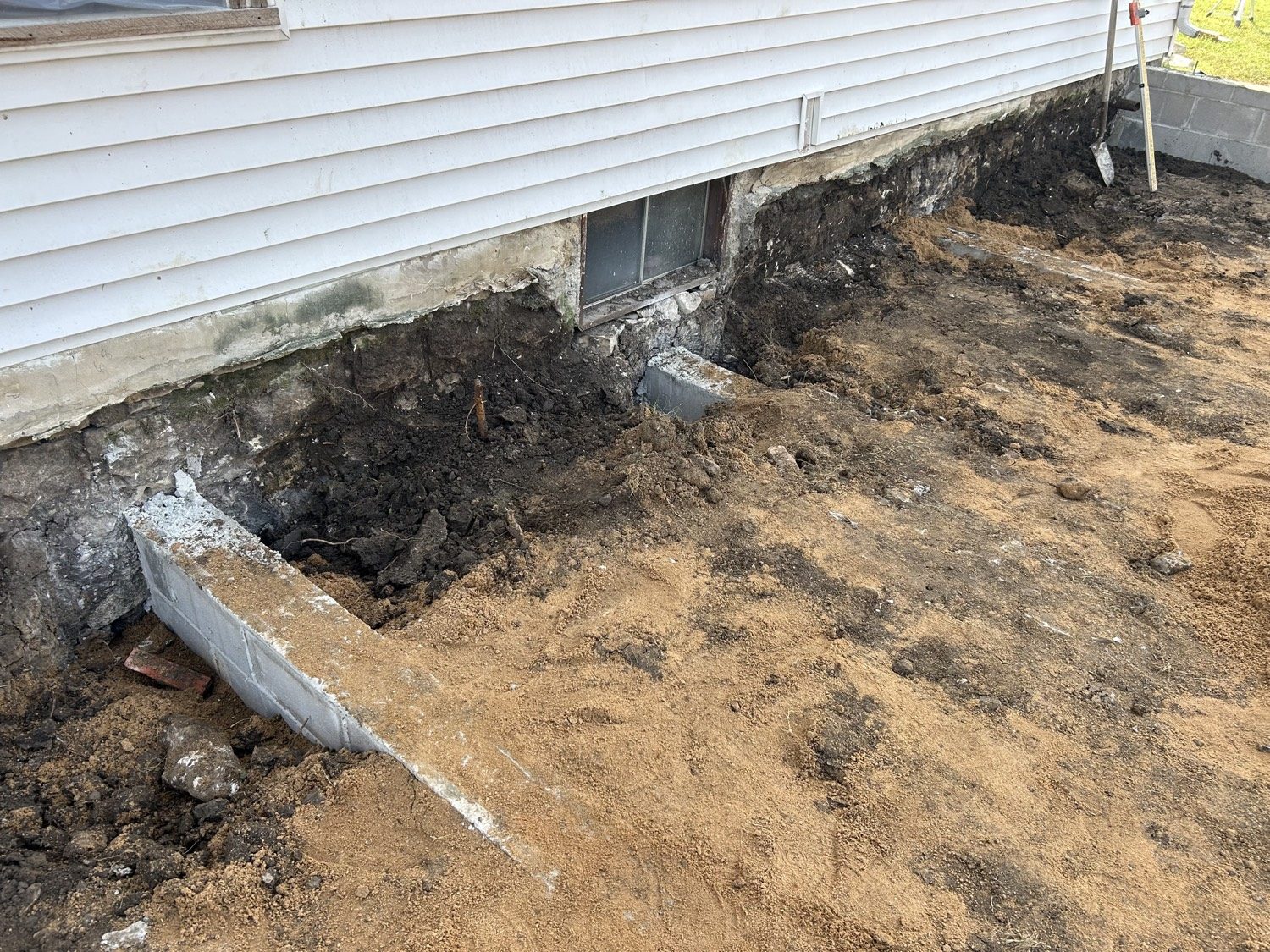 Exterior excavation with CMU deadman walls in the ground against the stone foundation