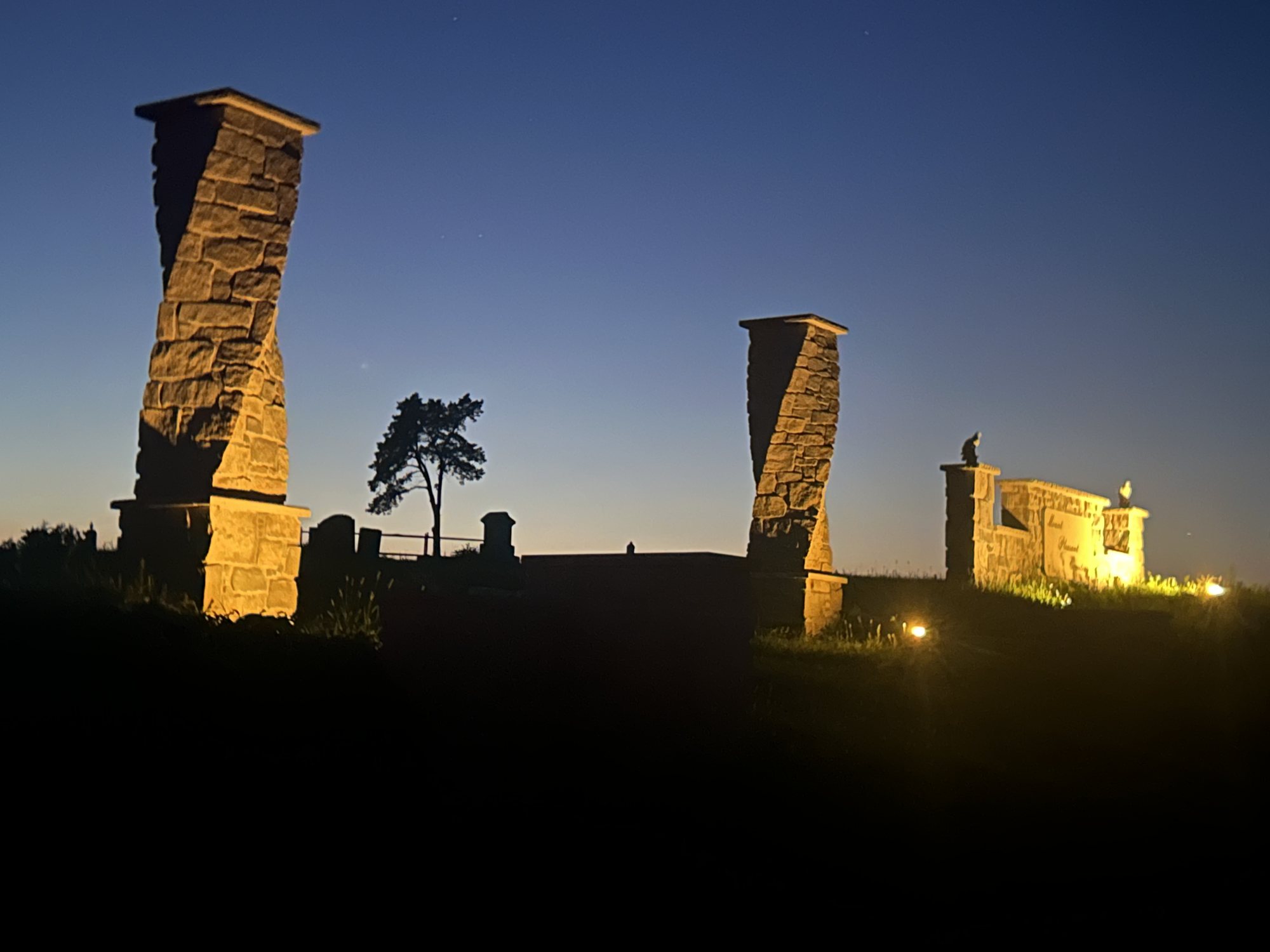 The same limestone columns uplit at dusk against a deep blue sky